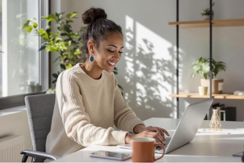 Woman in sunny room at her laptop