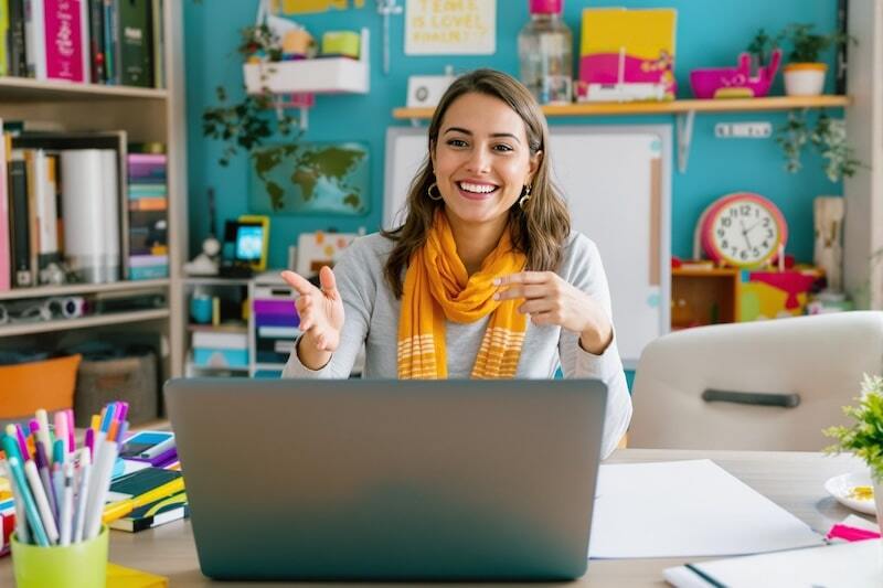 woman smiling and sitting in front of her laptop